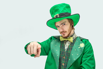 Serious young man in green suit point straight on camera. He wear St. Patrick's costume. Isolated...