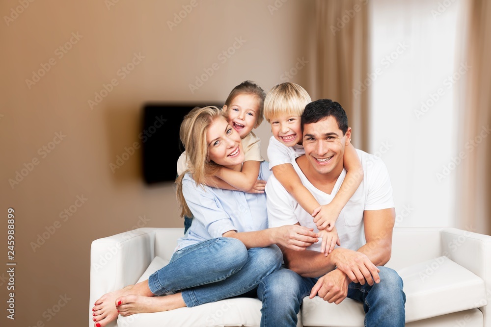 Wall mural Beautiful smiling family sitting at sofa at home