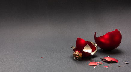 Red Christmas ball broken, dark gray background, closeup view