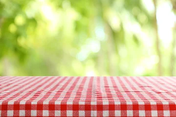 Fototapete Picknick Leerer Tisch mit karierter roter Serviette auf grünem unscharfem Hintergrund. Raum für Gestaltung