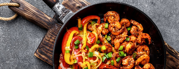 shrimp fajitas with bell pepper and onion cooked in a frying pan, top view, banner - 245989229