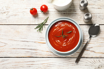 Bowl with fresh homemade tomato soup and space for text on wooden table, top view