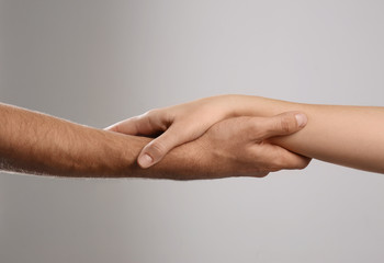 Man and woman holding hands on grey background, closeup. Help and support concept