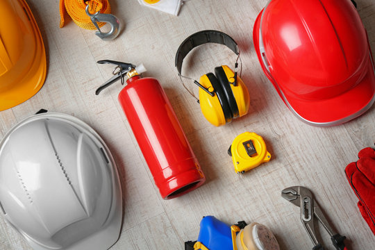 Flat lay composition with tools and safety equipment on wooden background