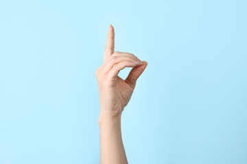 Woman showing D letter on color background, closeup. Sign language