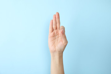 Woman showing F letter on color background, closeup. Sign language