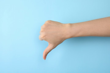 Woman showing thumb down sign on color background, closeup. Body language