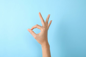 Woman showing sign okay on color background, closeup. Body language