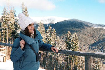 Fototapeta na wymiar Happy young woman spending winter vacation in mountains. Space for text