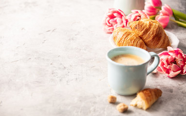 Morning coffee, croissants and spring tulips on light grey background