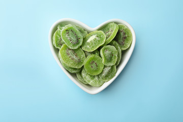 Bowl with slices of kiwi on color background, top view. Dried fruit as healthy food