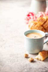 Morning coffee, croissants and spring tulips on light grey background