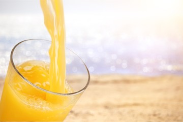 Orange juice glass on green blurred garden background, bokeh