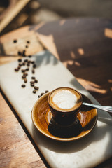 Fresh cappuccino standing on a marble plate early in the morning with bright sun, people ready to wake up and start a new working day, vertical image