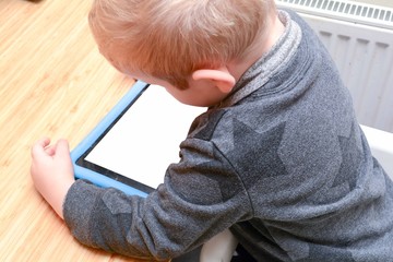 Child using a tablet device to learn and play games, model is young boy
