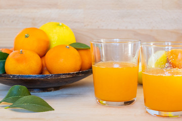 Fototapeta na wymiar Fresh juice of ripe mandarins and lemons in a small glass, selective focus