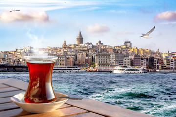 A cup of Turkish tea in a traditional glass against the background of the Golden Horn and the Galata Tower in Istanbul