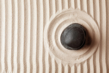 Fototapeta na wymiar Zen garden stone on sand with pattern, top view. Space for text