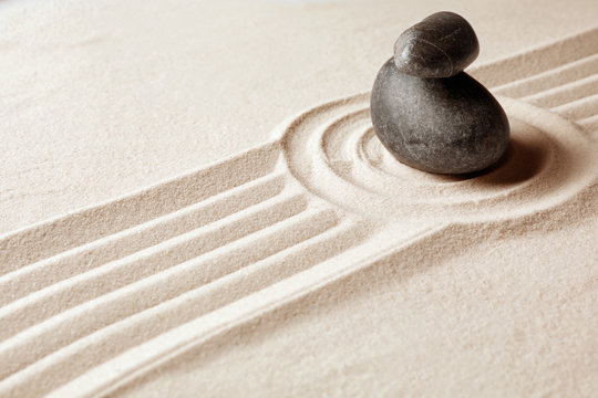 Stacked zen garden stones on sand with pattern, space for text. Meditation and harmony
