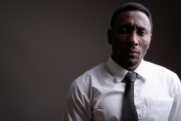 Fototapeta premium Young handsome African businessman against gray background