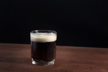dark beer in a glass on a wooden table