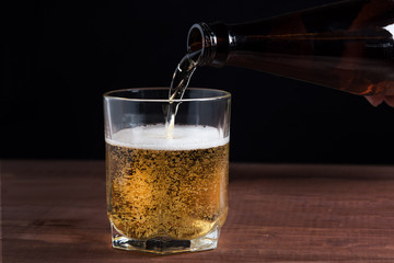 light beer with foam in a glass on a wooden table