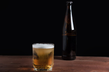 light beer with foam in a glass on a wooden table