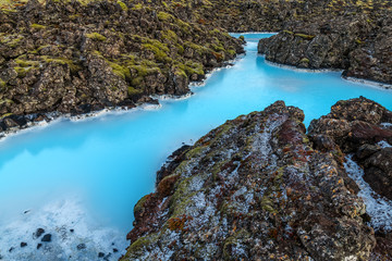 Beautiful volcanic terrain with black volcanic rocks and turquoise water at blue lagoon geothermal spa in Iceland