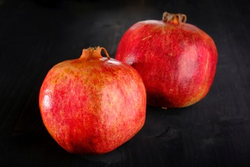 Fototapeta na wymiar two pomegranates on a black wooden background