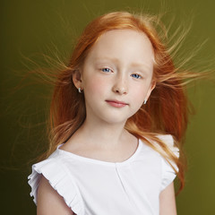 Beautiful red-haired girl with long hair and beautiful big blue eyes. Redhead Girl child in summer...