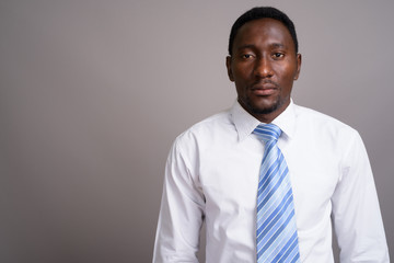 Young handsome African businessman against gray background