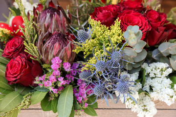 Easter decor. Festive flower arrangement of Protea, red roses, limonium sinuatum, eryngium, eucalyptus leaves and other plants in the flowers shop.