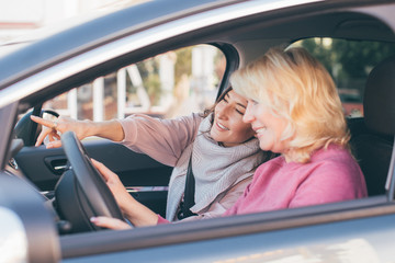 Blond hair woman driving - two women in the car looking for the right way - mother and daughter traveling together