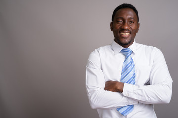 Young handsome African businessman against gray background