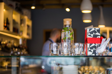 Bottle of water with glasses in the cafe with people at the background