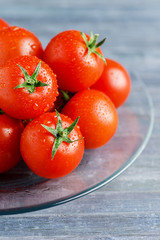 Fresh tomatoes on trasparent dish on wooden blue background