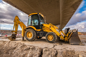 Backhoe in construction tasks of a road. Preparation of the land for the construction of a bridge...