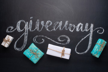 The inscription giveaway written on a blackboard with gifts. The distribution of gifts