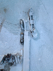 Aerial photo of frozen ship in ice of Lake Baikal. There is snow everywhere.