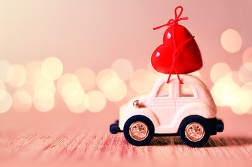 Little pink car carries a heart. The concept of Valentine Day.