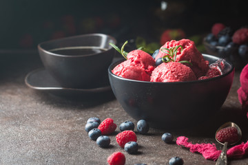 Homemade berry ice cream in a black bowl on a rustic background.