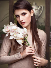 Young beautiful brunette business woman florist holding orchid branch of fresh flowers in flower shop