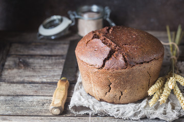 Fresh homemade traditional round rye bread on rustic wooden background