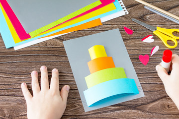 The child cuts out Greeting card with birthday cake congratulation. Children's art project craft...