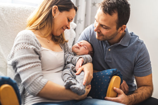 Parents and Baby having wonderful time sit on chair one the bedroom