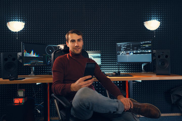 Young man working in the studio using a smartphone and computer.