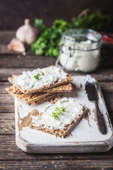 Crispbread toast with homemade herb and garlic cottage cheese on wooden background
