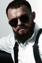 young handsome man with big beard and black sunglasses on white background  