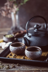 Still-life of japanese healthy green tea in a small cups and teapot over dark background