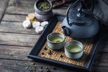 Still-life of japanese healthy green tea in a small cups and teapot over dark background
